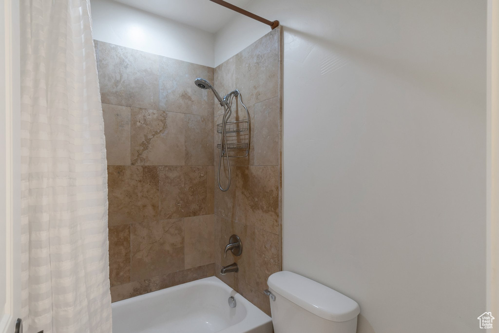 Bathroom featuring shower / tub combo with curtain and toilet