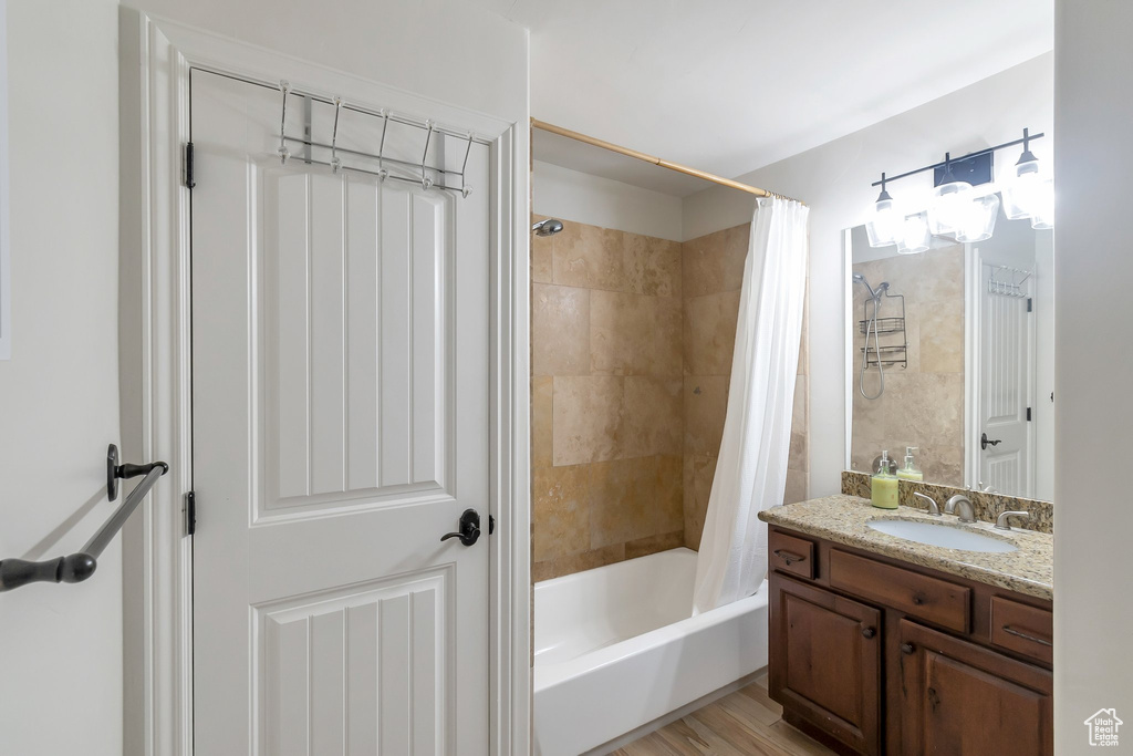 Bathroom featuring vanity, shower / bath combo with shower curtain, and hardwood / wood-style floors