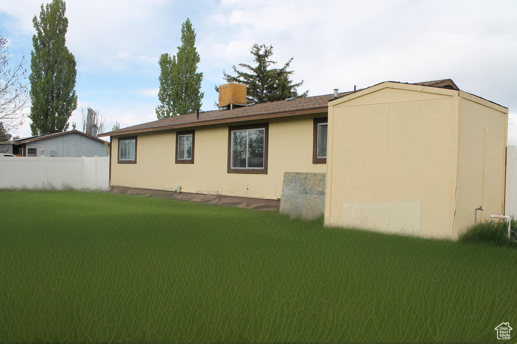 Rear view of property featuring a yard and fence