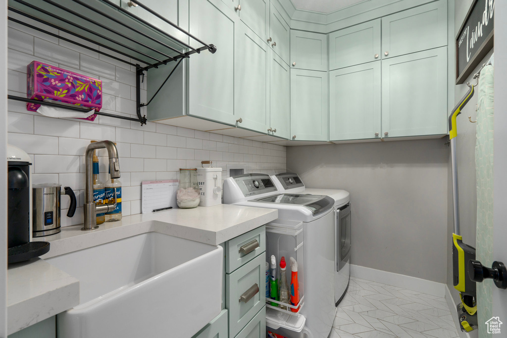 Washroom featuring washing machine and dryer, sink, and cabinets