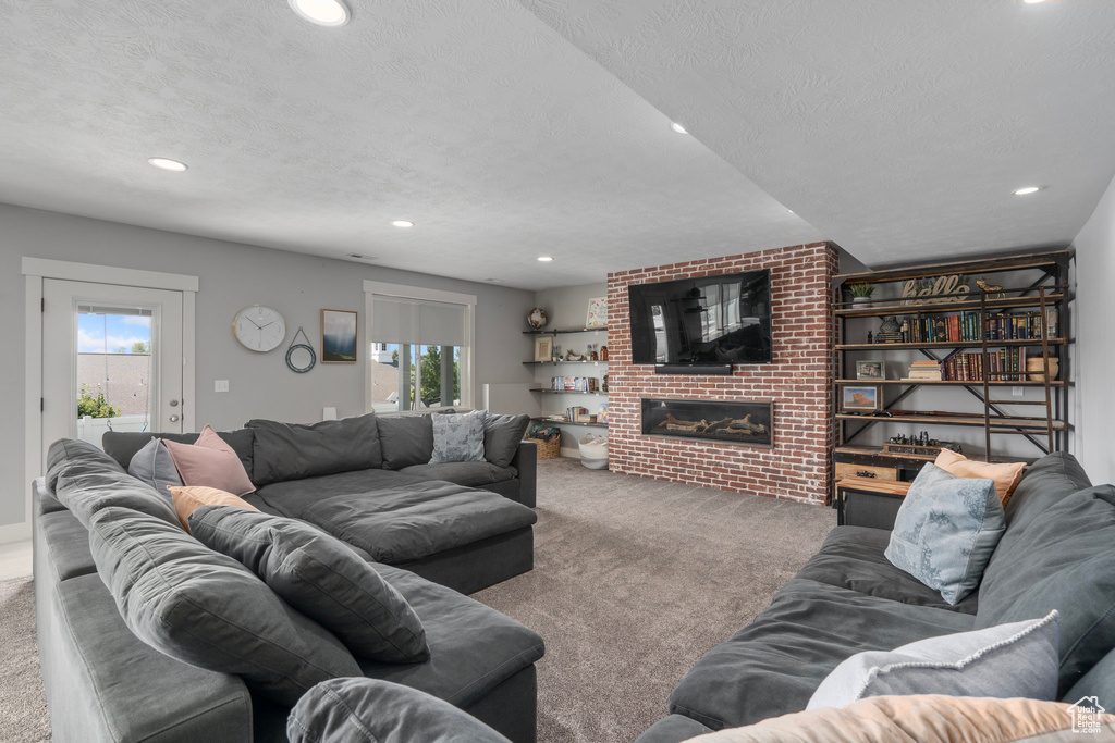 Carpeted living room with a brick fireplace and a textured ceiling