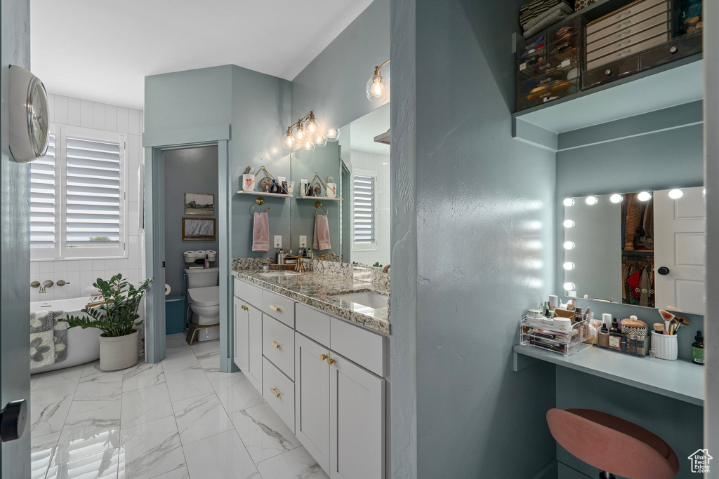 Bathroom with vanity, a tub to relax in, and toilet