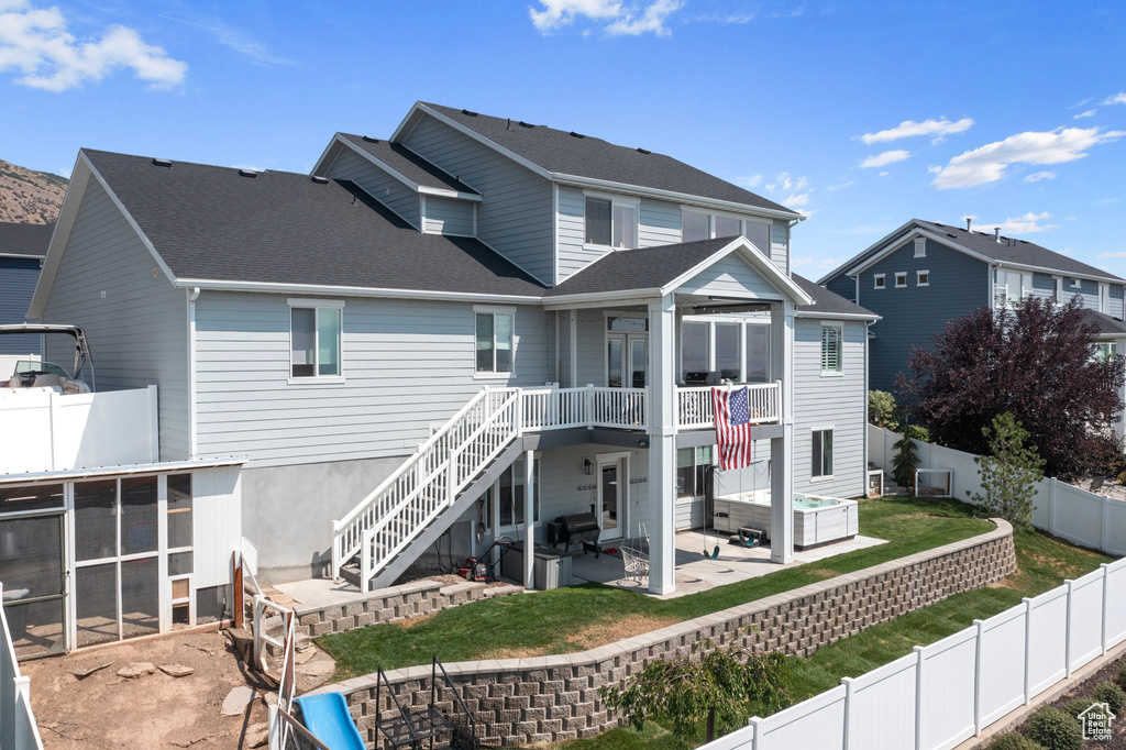 Rear view of house featuring a sunroom, a patio, and a lawn