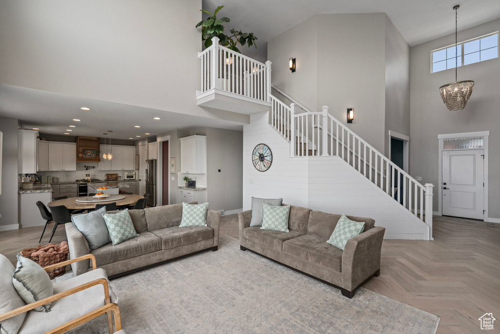 Living room featuring light parquet flooring, an inviting chandelier, and a towering ceiling