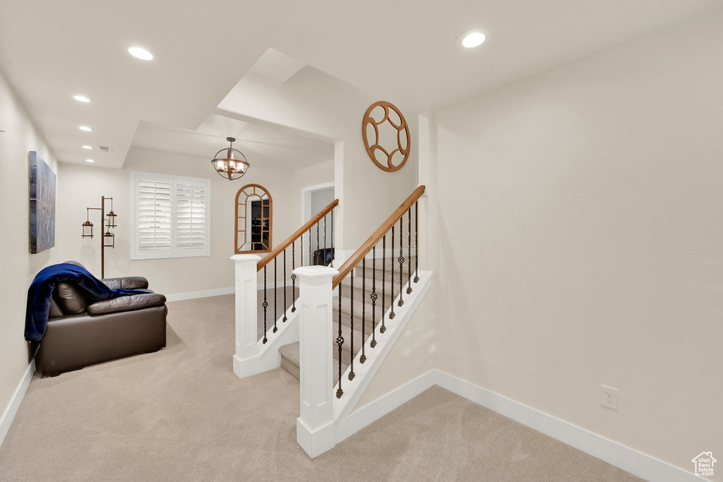 Stairway featuring a notable chandelier and carpet flooring