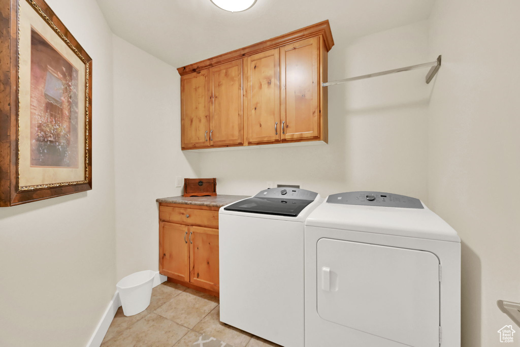 Laundry room featuring light tile patterned floors, cabinets, and independent washer and dryer