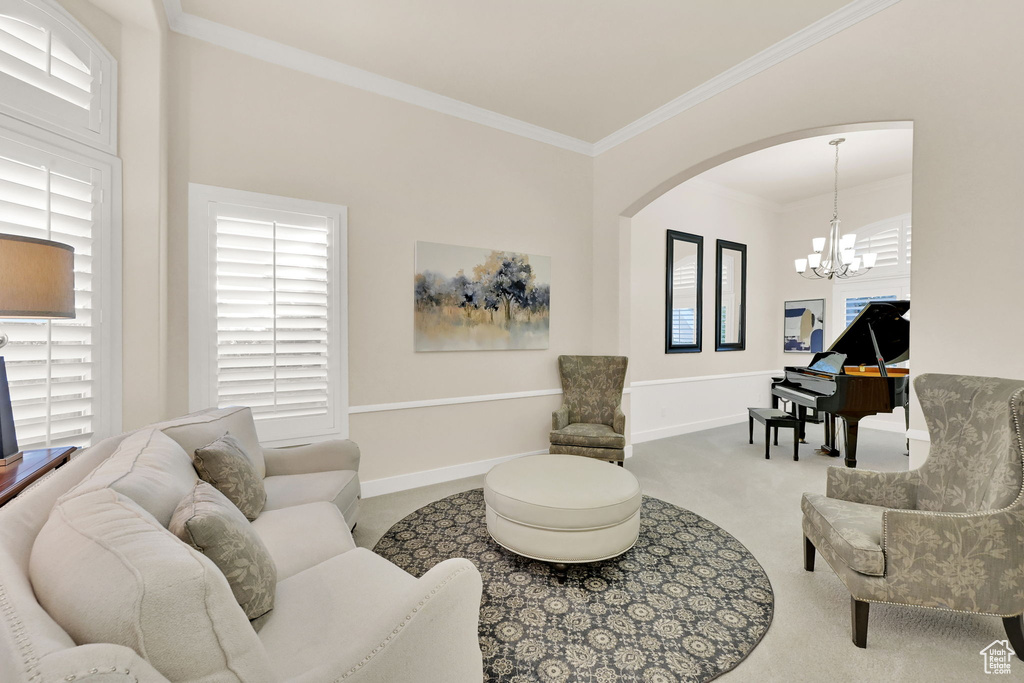 Living room with ornamental molding, a chandelier, and carpet floors