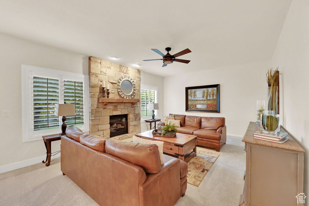 Living room with ceiling fan, light colored carpet, and a fireplace