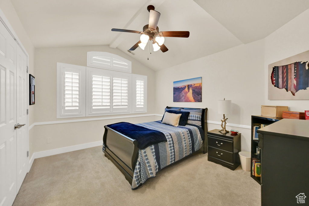 Carpeted bedroom featuring ceiling fan, a closet, and vaulted ceiling