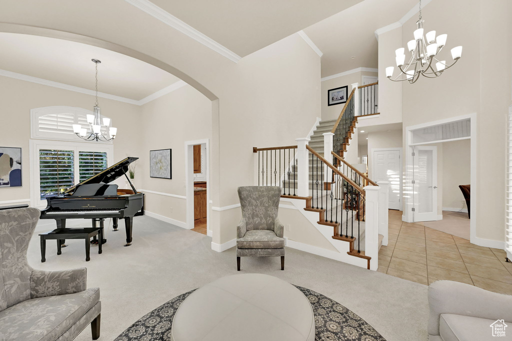 Living room featuring crown molding, a towering ceiling, an inviting chandelier, and tile patterned floors