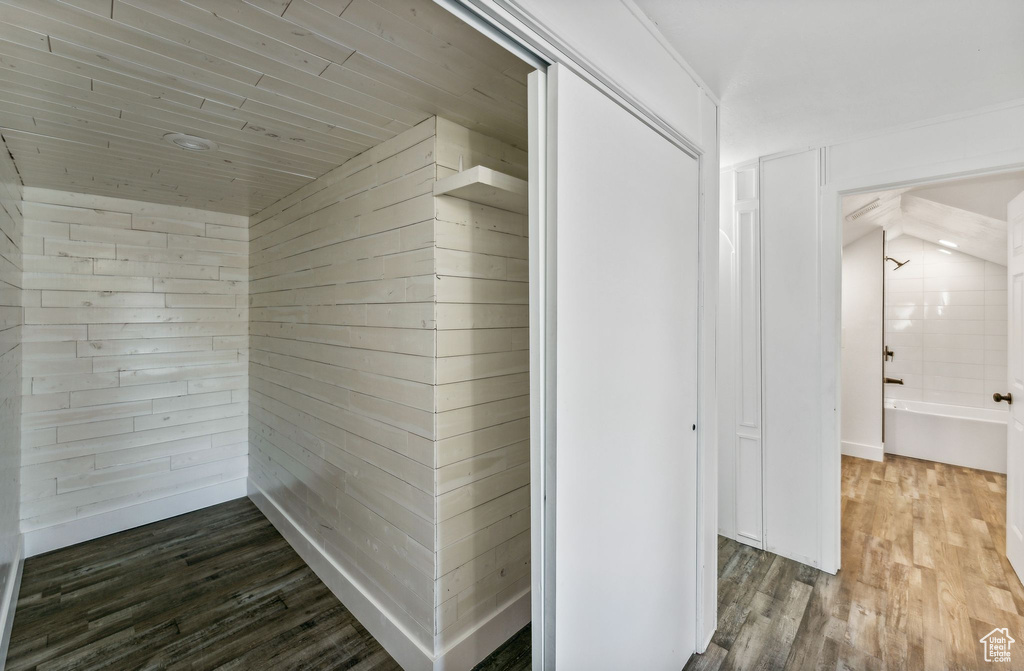 Hallway with lofted ceiling, dark hardwood / wood-style floors, and wood walls