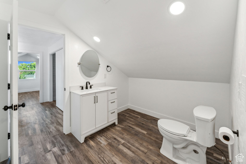 Bathroom with wood-type flooring, toilet, vanity, and vaulted ceiling