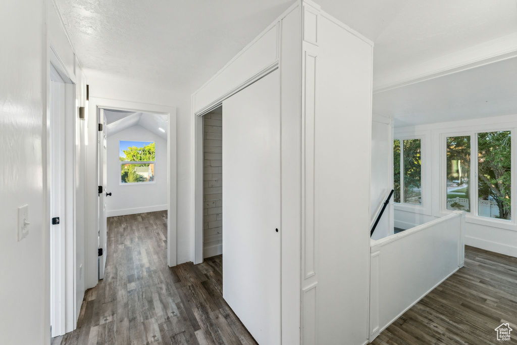 Hallway with vaulted ceiling and dark wood-type flooring