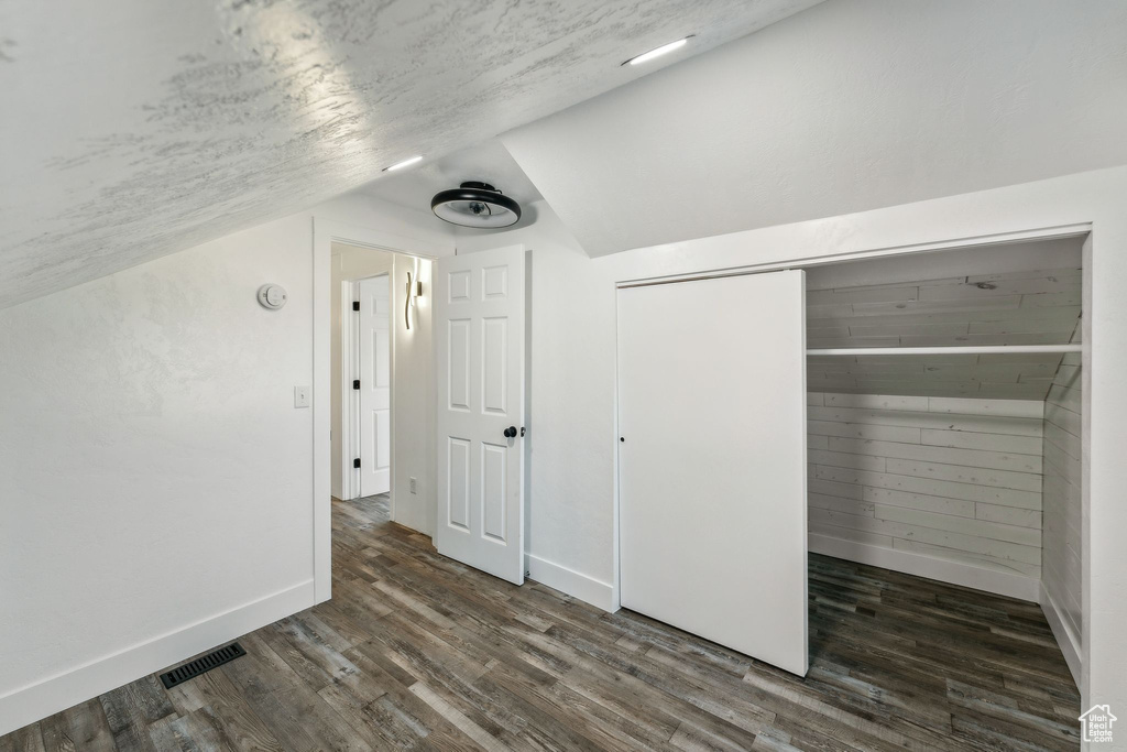 Additional living space with vaulted ceiling and dark hardwood / wood-style flooring