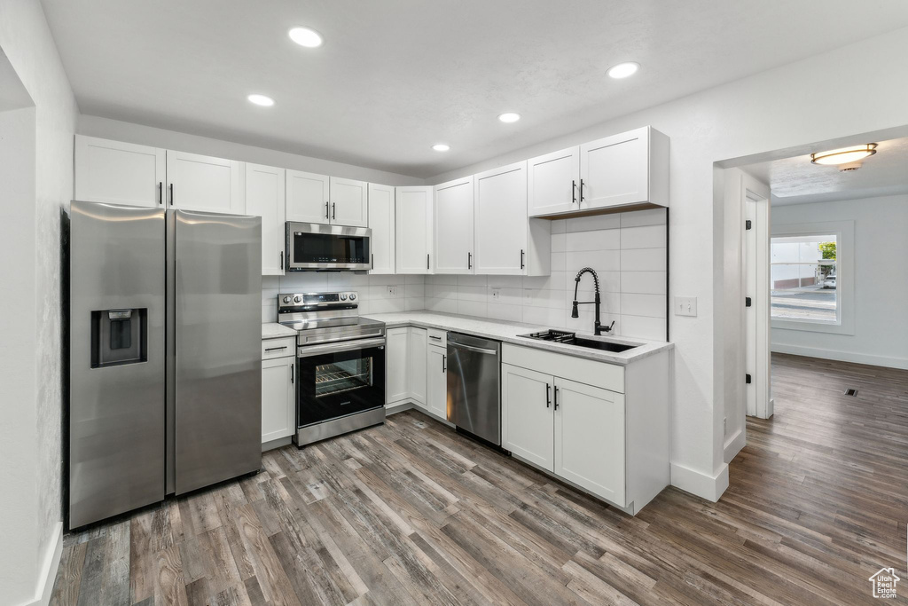 Kitchen with appliances with stainless steel finishes, dark hardwood / wood-style floors, sink, and white cabinetry