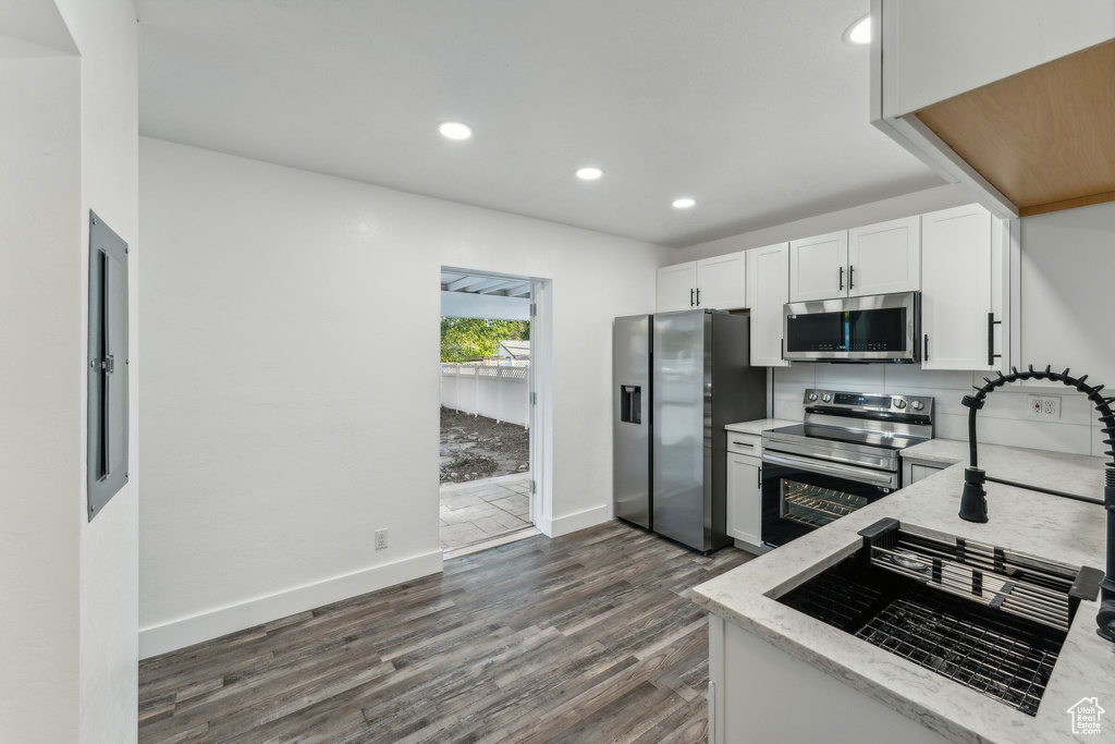 Kitchen with light stone counters, white cabinets, stainless steel appliances, and dark hardwood / wood-style floors