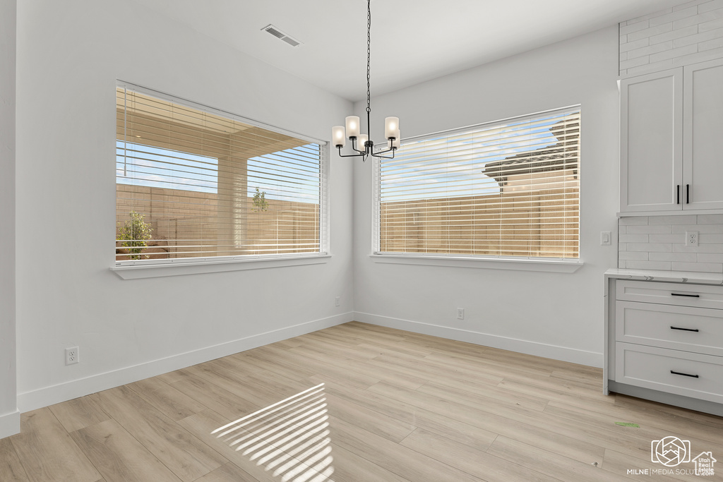 Unfurnished dining area featuring light hardwood / wood-style flooring and a chandelier