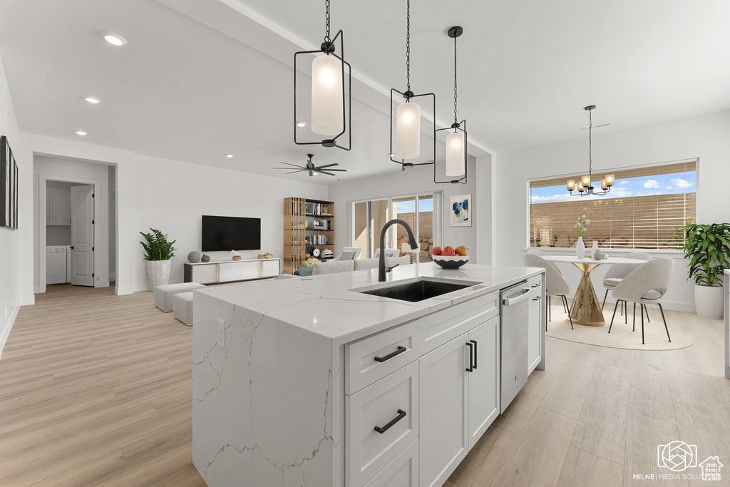 Kitchen with light stone countertops, sink, an island with sink, hanging light fixtures, and white cabinets