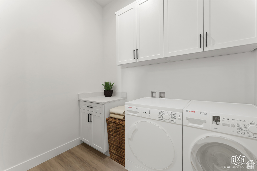 Washroom featuring light hardwood / wood-style flooring, cabinets, and washer and clothes dryer