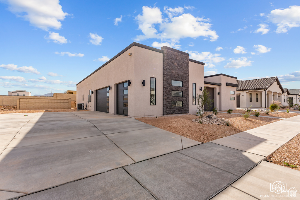 View of front of house with central AC unit and a garage