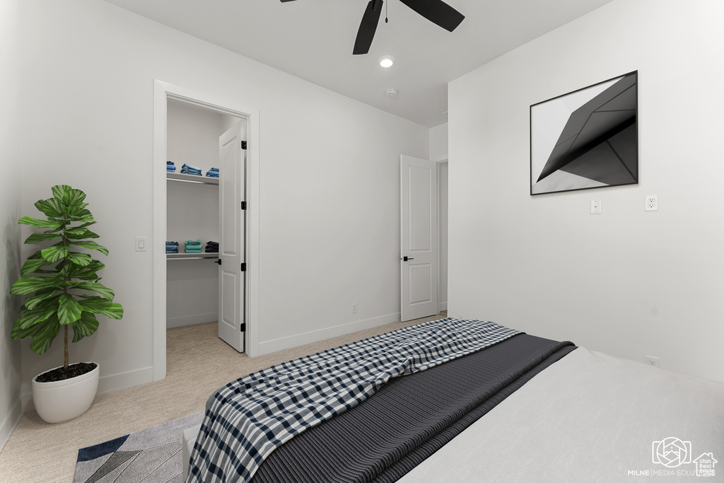 Carpeted bedroom featuring ceiling fan and a walk in closet