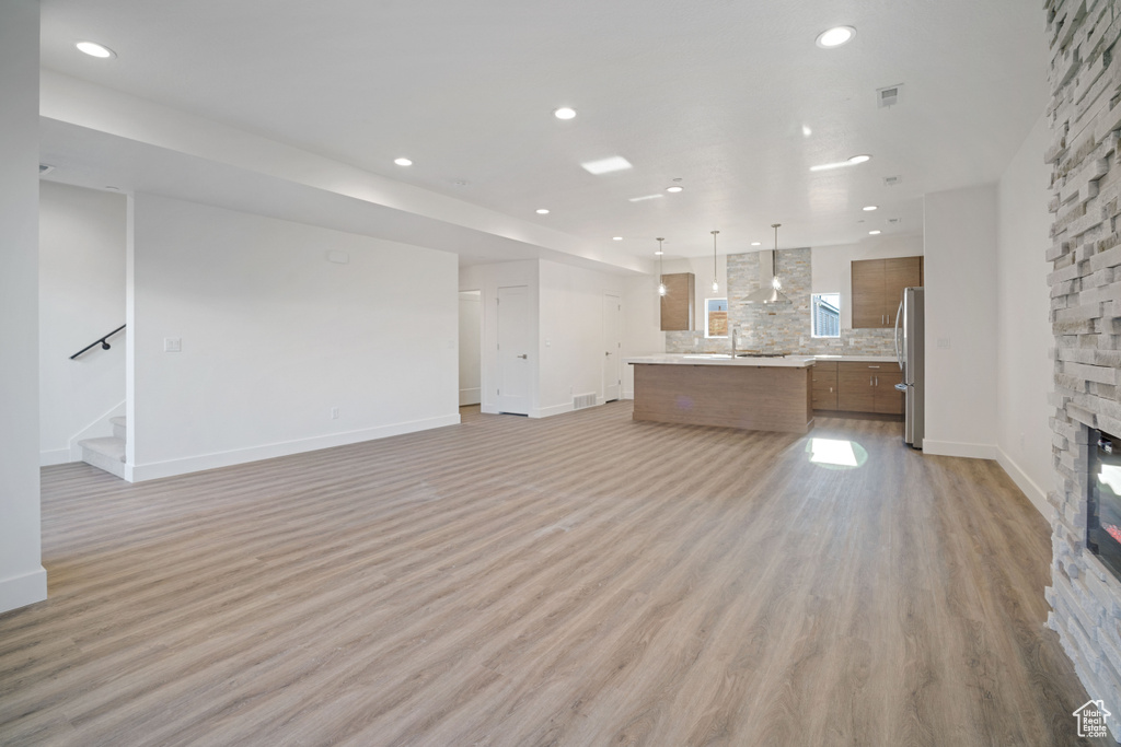 Unfurnished living room with light wood-type flooring, a fireplace, and sink