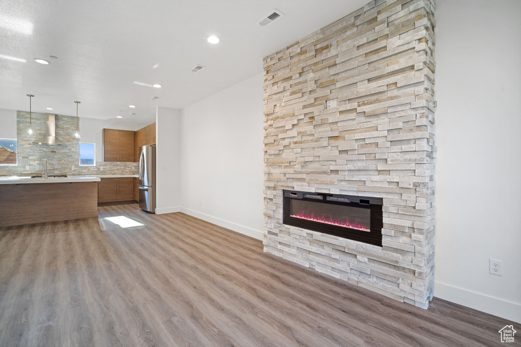 Unfurnished living room with light wood-type flooring, a fireplace, and sink