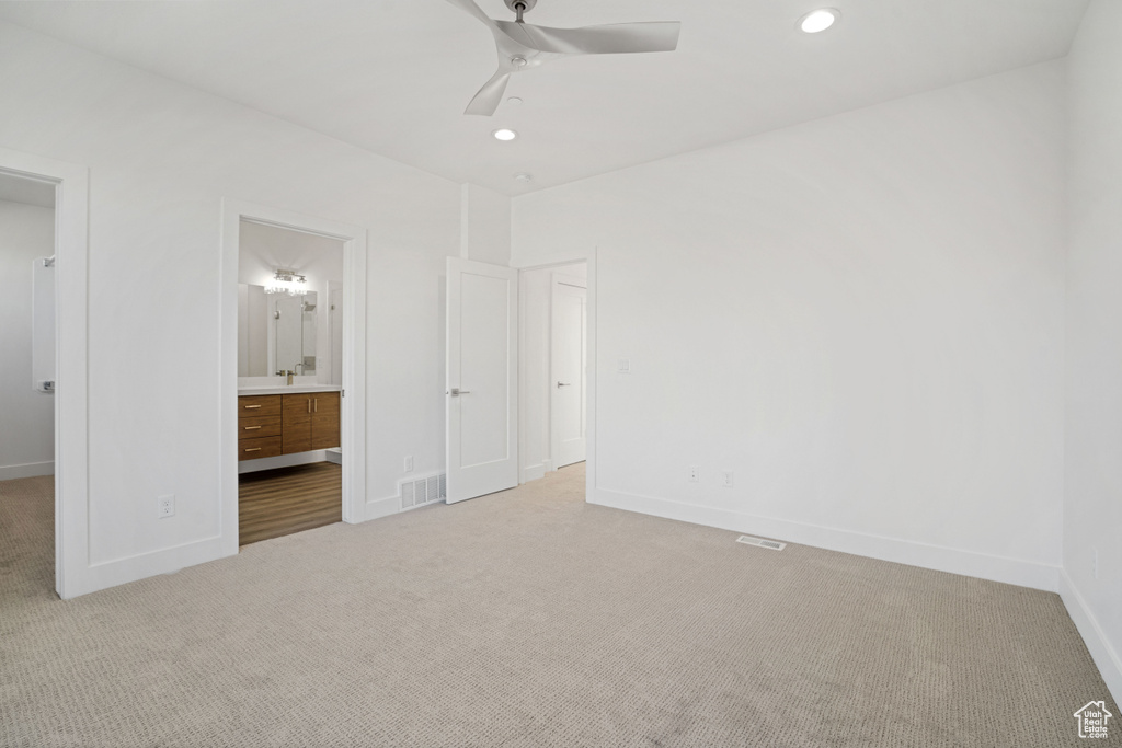 Unfurnished bedroom featuring connected bathroom, light carpet, and ceiling fan