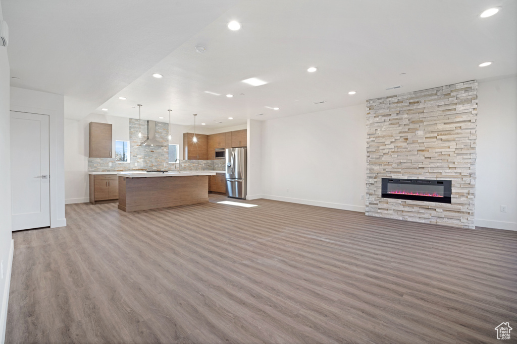 Unfurnished living room with a stone fireplace and light hardwood / wood-style flooring