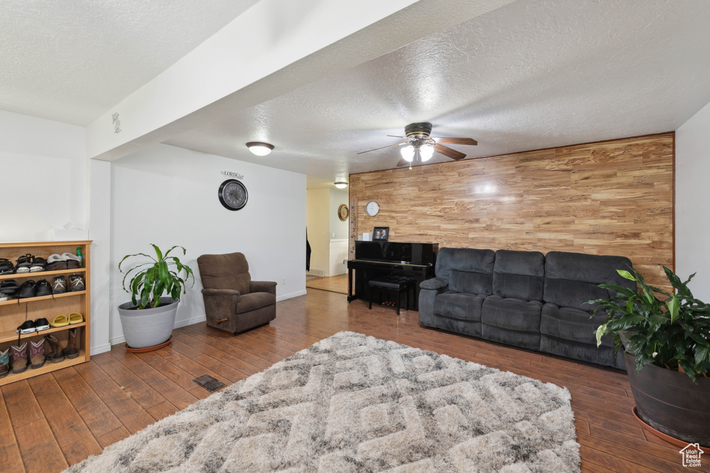 Living room with wooden walls, ceiling fan, and dark hardwood / wood-style flooring