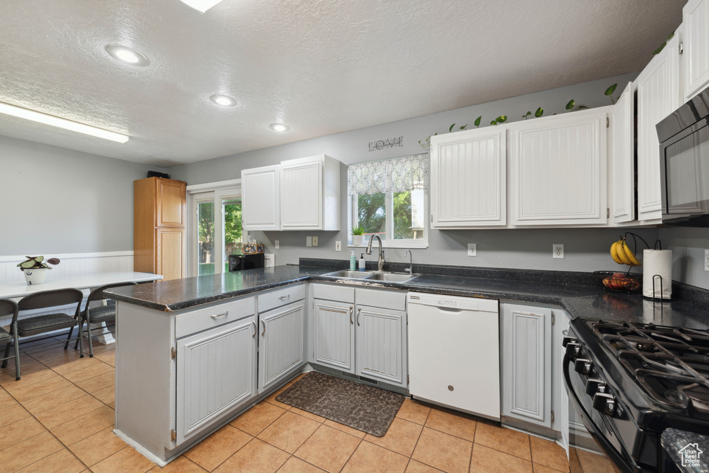 Kitchen with white cabinets, kitchen peninsula, dishwasher, gas stove, and sink