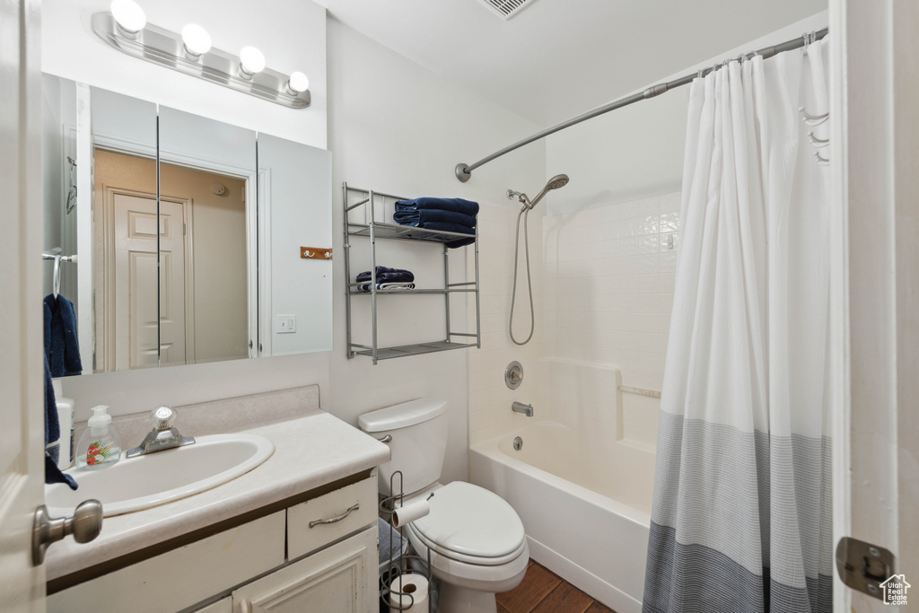 Full bathroom featuring shower / tub combo, hardwood / wood-style flooring, vanity, and toilet