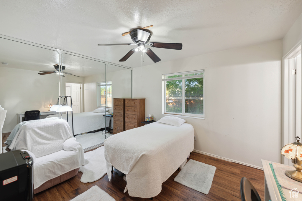 Bedroom with ceiling fan, dark wood-type flooring, and a textured ceiling