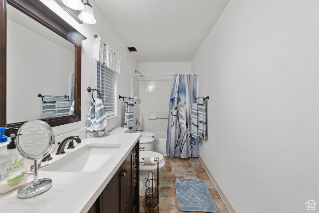 Full bathroom featuring vanity, shower / bath combo with shower curtain, and toilet