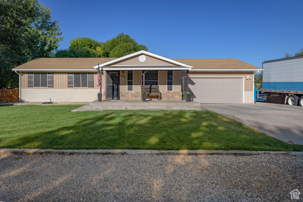 Ranch-style house featuring a front lawn, a porch, and a garage