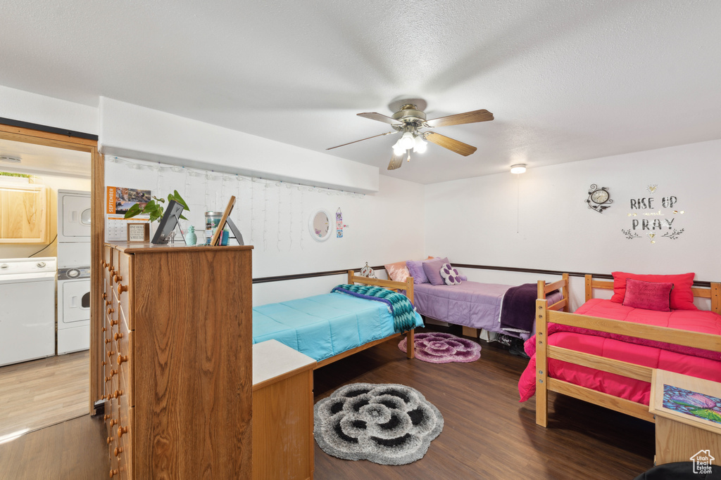 Bedroom with stacked washer / drying machine, wood-type flooring, a textured ceiling, and ceiling fan