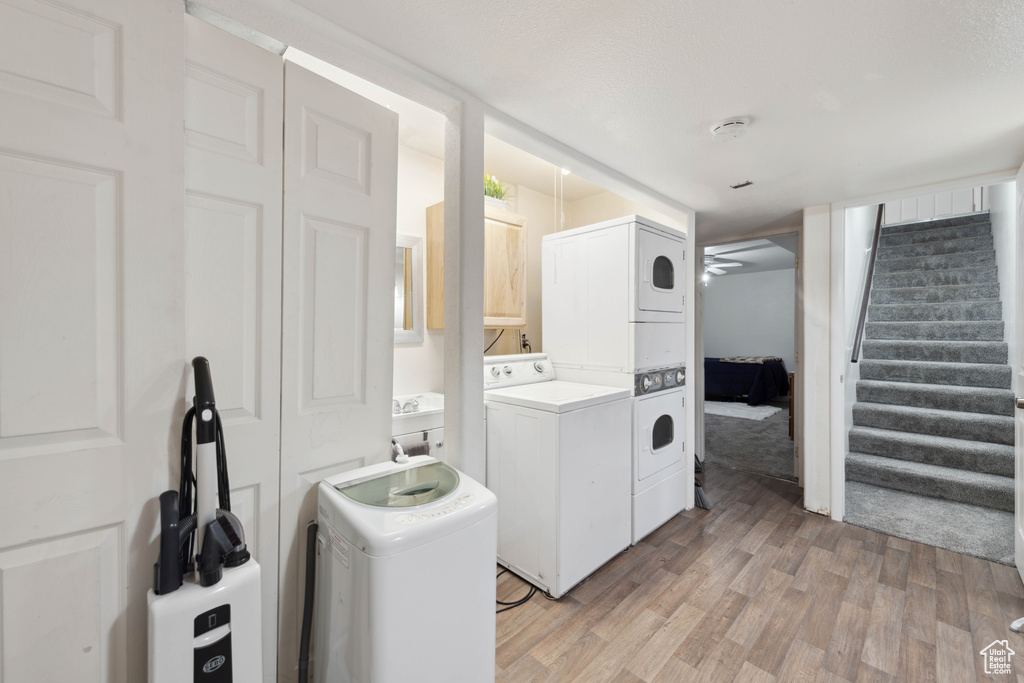 Clothes washing area with stacked washer and clothes dryer, light hardwood / wood-style floors, and washing machine and clothes dryer