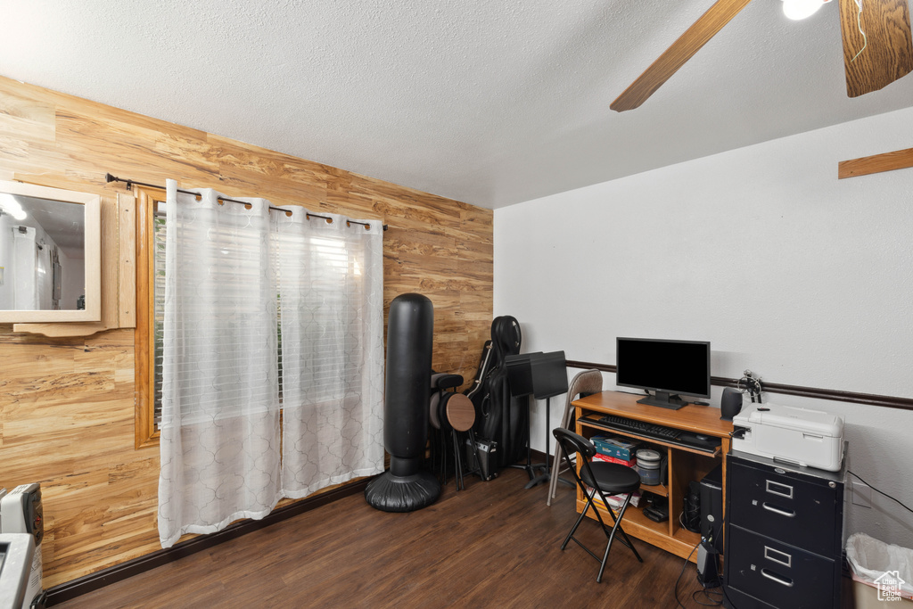 Office area with wooden walls, ceiling fan, a textured ceiling, and dark hardwood / wood-style flooring