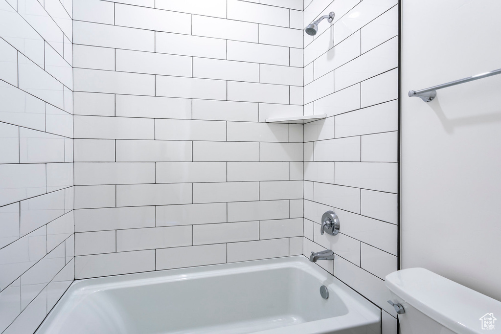 Bathroom with tiled shower / bath combo and toilet