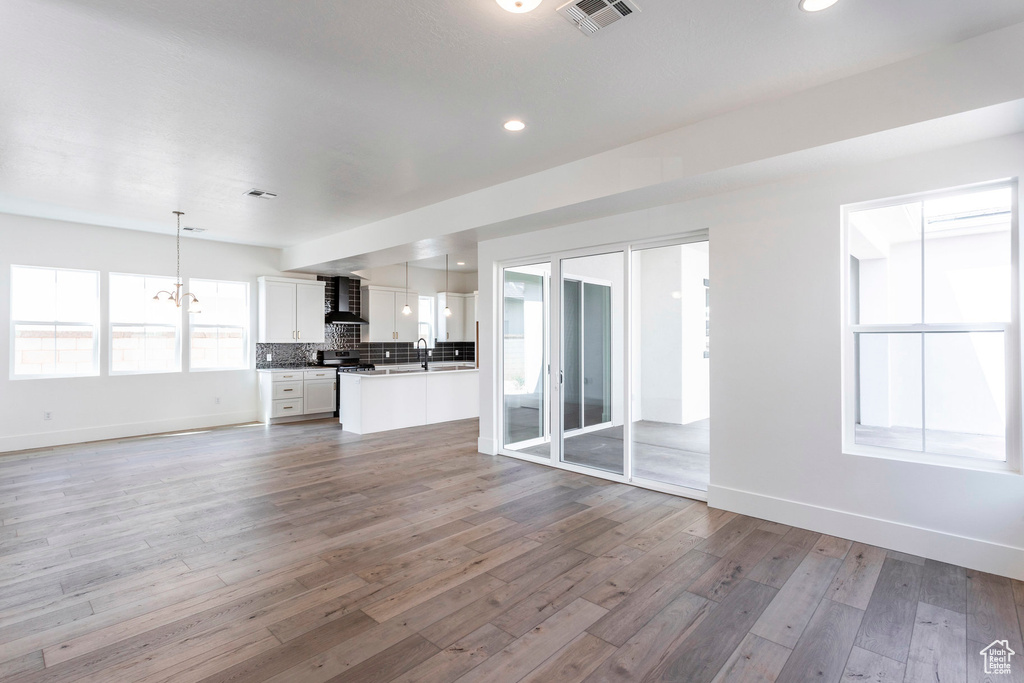 Unfurnished living room with a chandelier, light hardwood / wood-style floors, and sink