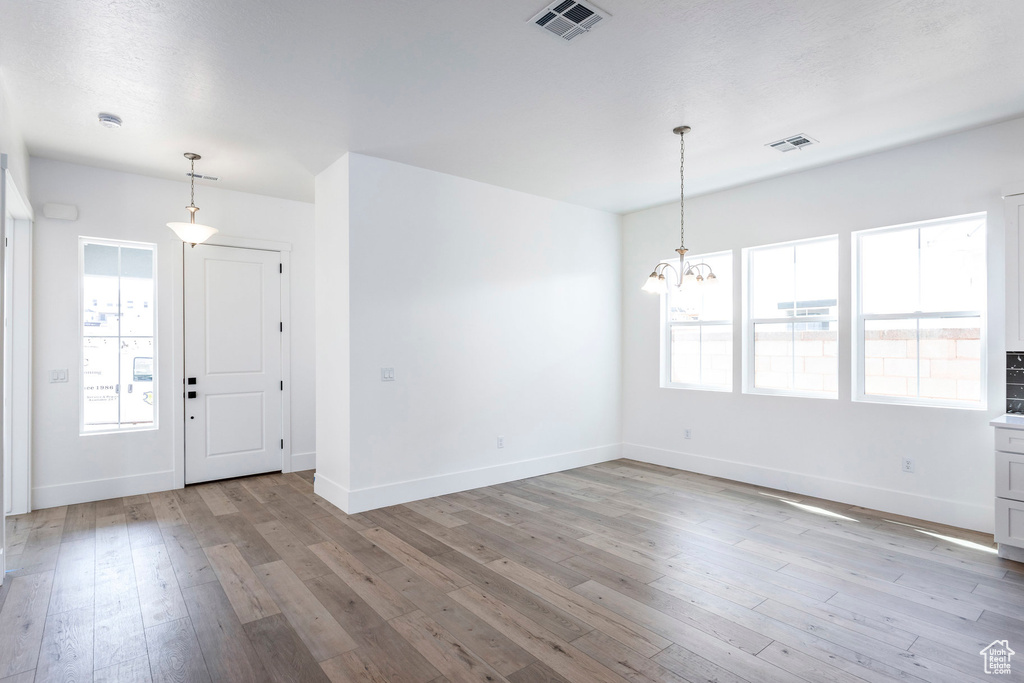 Interior space with a notable chandelier, plenty of natural light, and light hardwood / wood-style floors