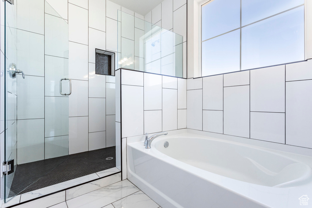 Bathroom featuring tile walls and separate shower and tub