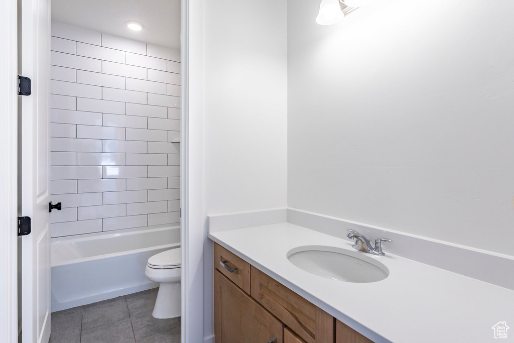 Full bathroom with tiled shower / bath, vanity, tile patterned flooring, and toilet