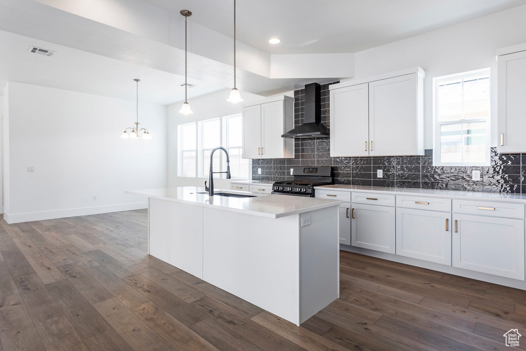 Kitchen featuring white cabinets, an island with sink, and sink