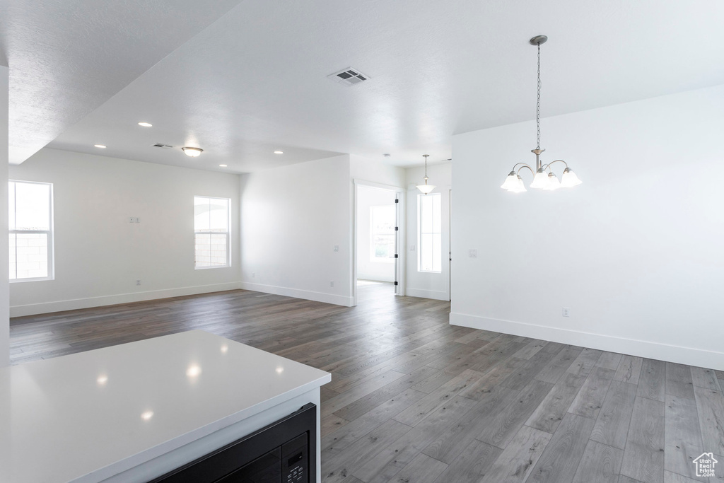 Unfurnished living room featuring a chandelier and hardwood / wood-style floors