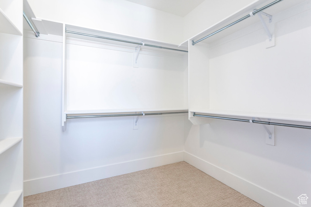 Walk in closet featuring light colored carpet