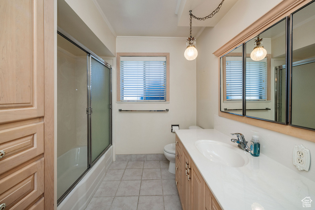 Full bathroom with enclosed tub / shower combo, vanity, tile patterned flooring, crown molding, and toilet