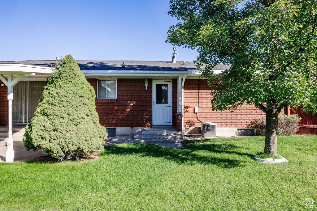 Rear view of house with a lawn and central AC unit