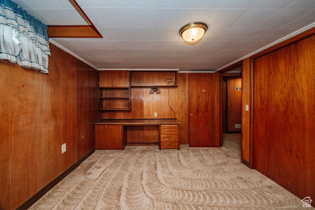 Carpeted office space with wooden walls and built in desk