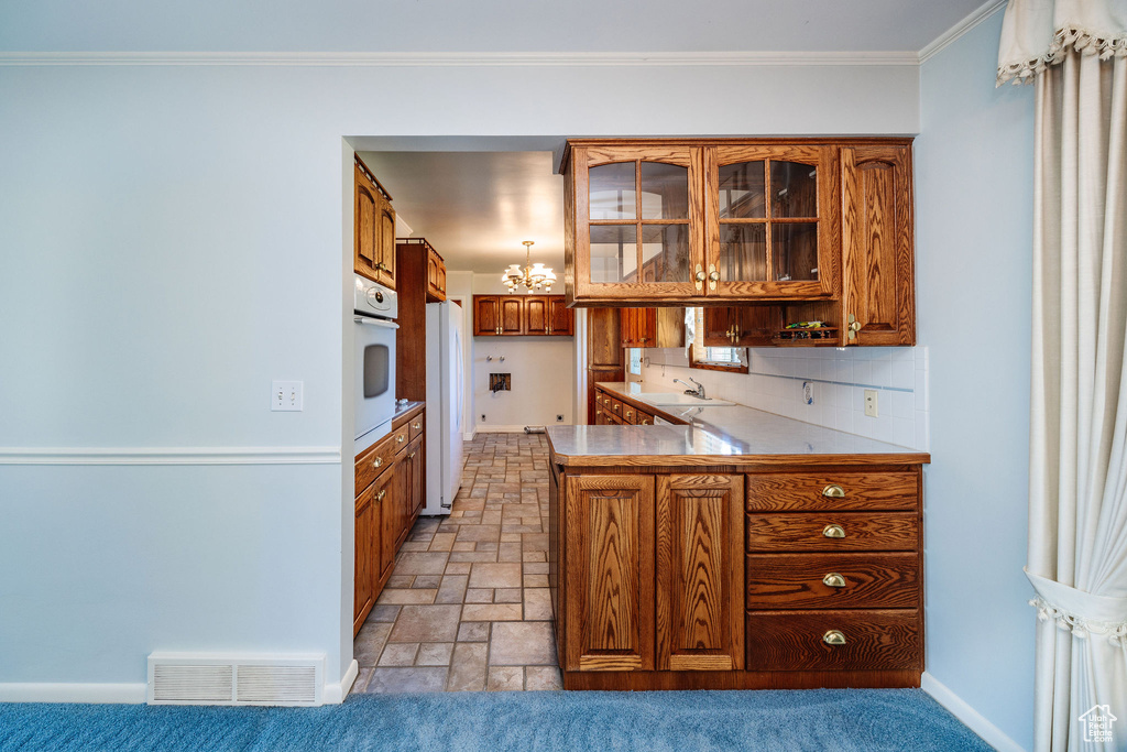 Kitchen featuring ornamental molding, sink, kitchen peninsula, and white appliances